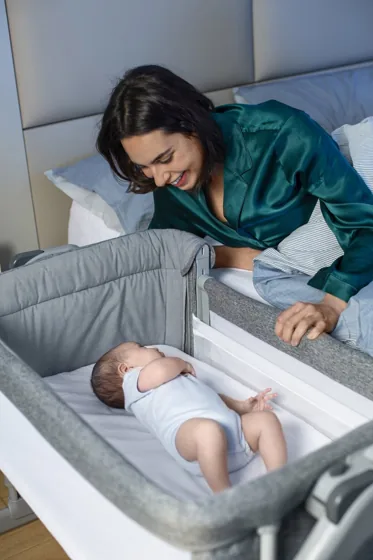 Une maman près de son bébé dans le berceau cododo Chicco Next2Me Magic Evo